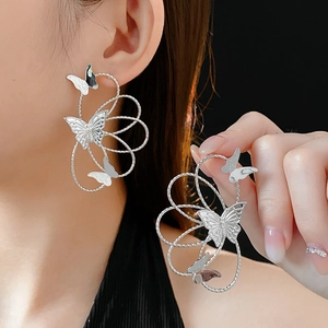 Detailed close-up of hollow butterfly earrings in silver with elegant metal texture