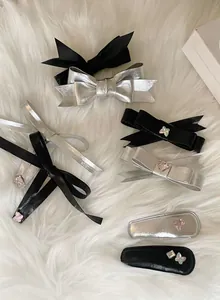 Close-up of black and silver bow hair clips with pink rhinestone heart and butterfly details