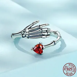 Gothic 925 sterling silver skull hand ring holding a vibrant red heart zircon stone