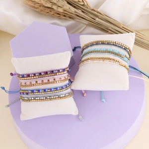 Detailed view of colorful beaded woven bracelets in multiple colors on white cushions