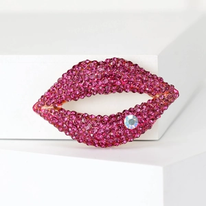 Detail of pink crystal lip brooch with sparkling rhinestones on a white display stand