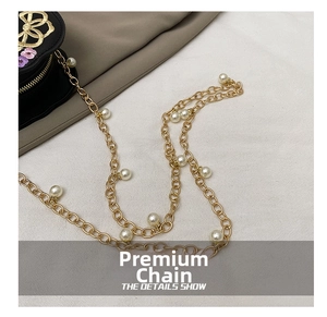 Detailed macro view of golden metal chain with pearls on floral embroidery handbag