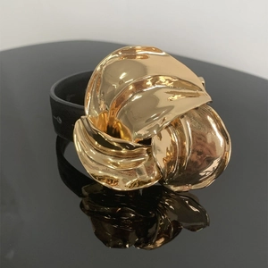 Detailopname van een luxe leren armband met een groot goudkleurig metalen bloemaccent