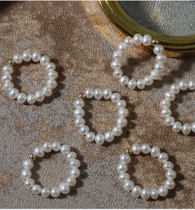 Macro detail of natural freshwater pearl rings with 14K gold-filled accents on stone surface
