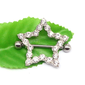 Close-up of star-shaped stainless steel nipple ring with rhinestones on a leaf