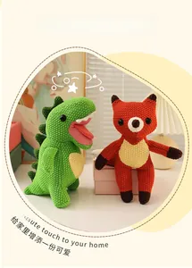 Detail of handmade crochet green dinosaur and orange fox knitted plush toys in home setting