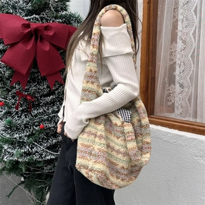 Detail of plush striped tote bag with plaid lining shown on a model in a festive setting