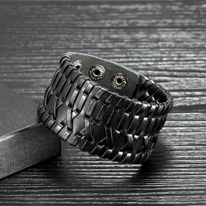 Punk style men's black woven leather bracelet with metal snap button on wood background