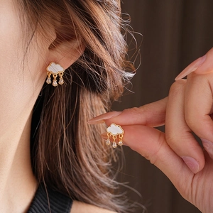 Cloud shell earrings with hanging zircon raindrops and gold-plated edges worn on ear