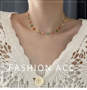Close-up of a colorful enamel daisy flower necklace on a model with gold chain detail