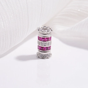 Macro shot of silver cylinder bead with ruby-red stones and clear zircon crystals