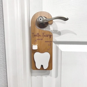 Detail of wooden tooth fairy door hanger featuring tooth pocket and engraved instructions