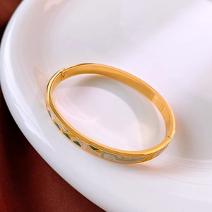 Vue détaillée d'un bracelet en titane doré avec motifs en émail vert et jaune sur plateau