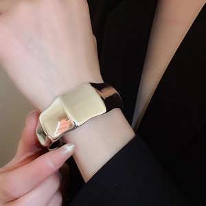 Close-up of a wide silver irregular textured cuff bracelet worn on a model's wrist