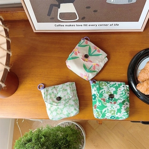 Detail of mini floral pouches with metal snap buttons and purple hooks on wooden table