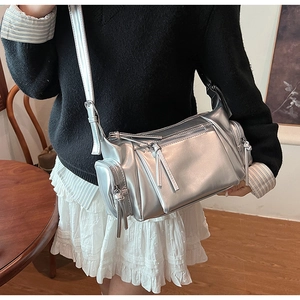 Gros plan du sac bandoulière argenté métallisé avec poches zippées et sangle réglable