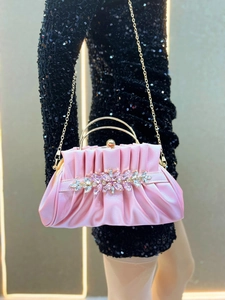 Detailed shot of pink satin evening clutch with crystal floral patterns and gold handles