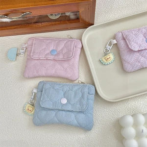 Detailed view of macaron-colored quilted coin purses with cute bear charms in a soft setting