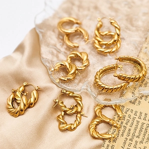 Macro shot of assorted gold twisted hoop earrings on silk background with vintage paper
