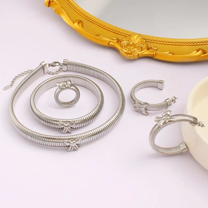 Détail d'un ensemble de bijoux argentés avec nuds et texture spirale sur miroir chic