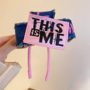 Detailed shot of large denim hair claw clip with pink graffiti and This Is Me patch