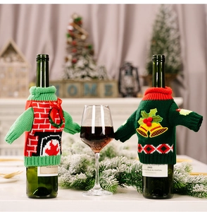 Close-up of festive knitted wine bottle covers with red fireplace and green bell patterns