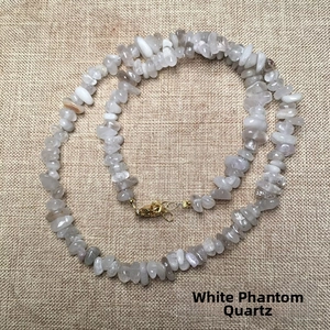 Macro shot of irregular white phantom crystal stone necklace with golden lobster clasp