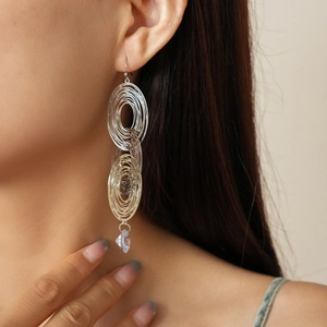 Detail of silver layered oval hoop earrings with clear crystal drop on a model