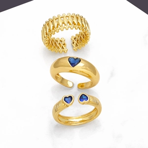 Three-piece gold adjustable ring set with blue heart gemstones on marble background