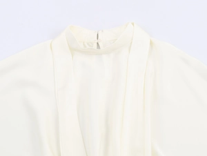 Detailweergave van de elegante crème satijnen jurk met opstaande kraag en plooien