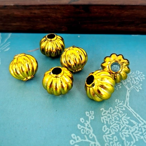 Macro shot of six gold pumpkin-shaped beads with a metallic finish on a blue background