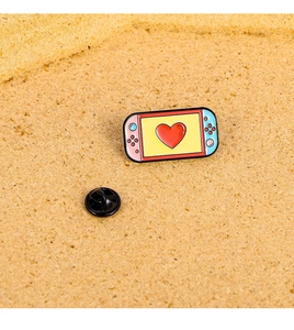 Detail shot of cute pink game console enamel pin with heart on a cork background