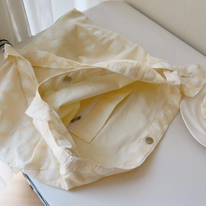 Macro view showing the magnetic snap closure and zippered inner pocket of the cream tote bag