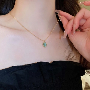 Elegant gold necklace with beaded chain and oval green cat eye stone pendant on model