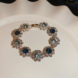 Macro detail of silver vintage flower bracelet with blue crystals on a white plate