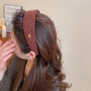 Détail d'un serre-tête en velours marron rouge avec plaque métallique dorée Corée