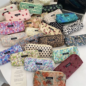Flat lay of floral and leopard print corduroy pencil cases on a white desk workspace