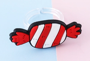Nahaufnahme eines Kinderrings mit buntem PVC-Bonbon-Anhänger und transparentem Ringband