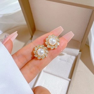 Detail of luxury gold stud earrings with white pearl and sparkling zircon petals
