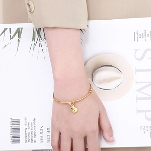 Women's gold titanium steel open bangle featuring a minimalist guitar musical charm pendant