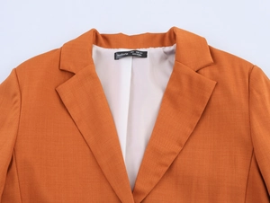 Detail of the orange blazer collar with lace stitching and size label S in macro view