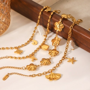 Gold stainless steel charm bracelets with star, moon, and floral pendants on wood tray