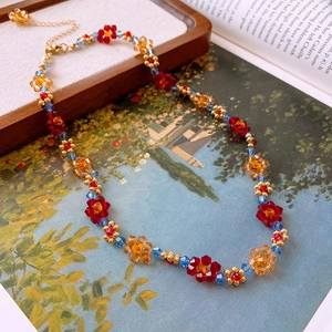 Détail d'un collier de perles fait main avec motifs floraux rouges et bleus en cristal
