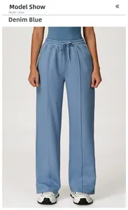 Detail view of denim blue sweatpants featuring drawstring waist and pleated leg seams