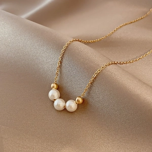 Elegant gold pearl necklace with three white pearls on a champagne velvet silk background