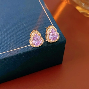 Detailed view of gold gourd earrings with pink gemstones on a navy jewelry box