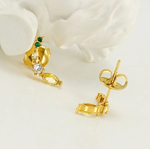 Détail macro d'une boucle d'oreille banane plaquée or 18K avec zircons colorés et fermoir papillon