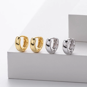 Detailed view of silver and gold S925 sterling silver hoop earrings on white blocks