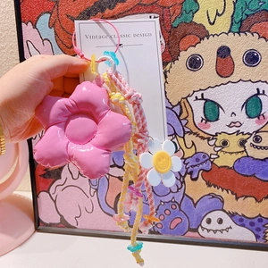 Gros plan du porte-clés fleur en cuir rose avec corde tressée colorée et charm sourire