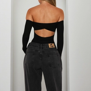 Detail of cross back cut-out and open-back design on a black long-sleeve bodysuit